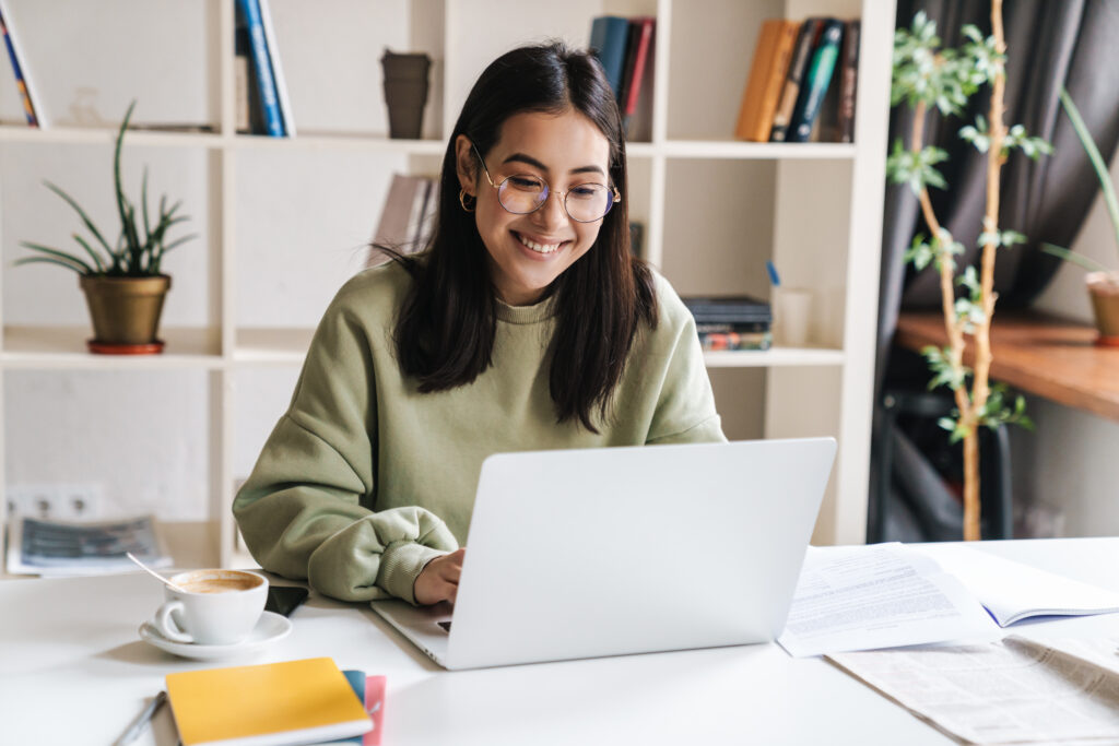 Person smiling and using laptop in a college library