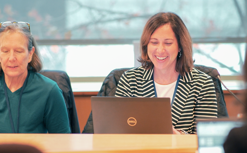 committee member smiling and looking down at laptop screen