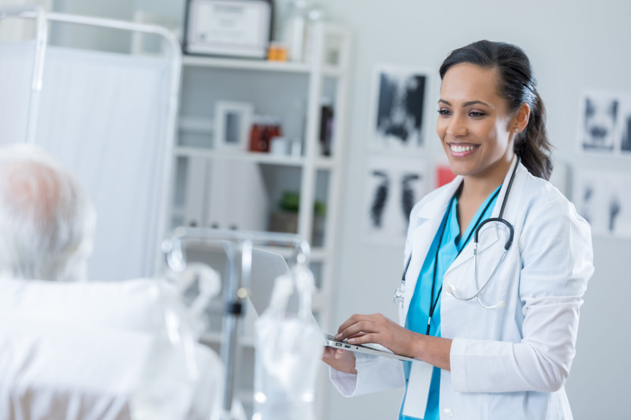 resident holding laptop and smiling at patient